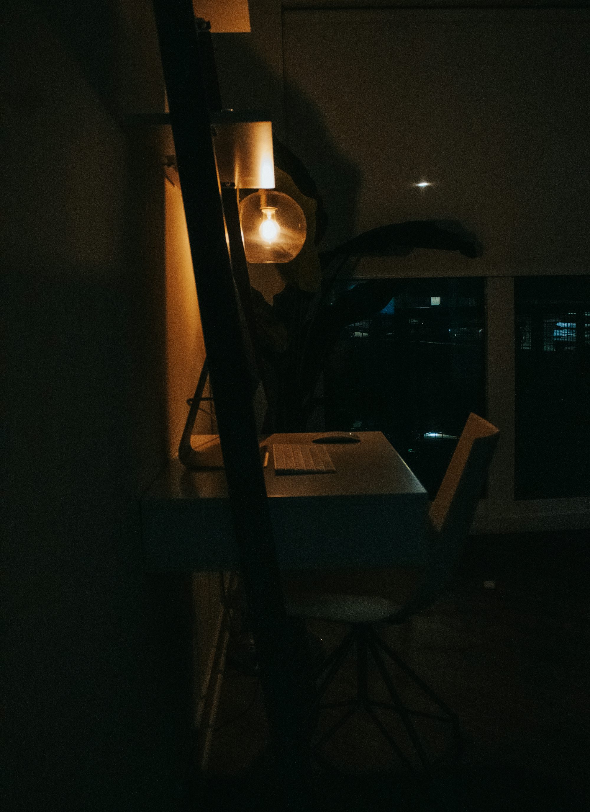 a dark room with a desk and a lamp