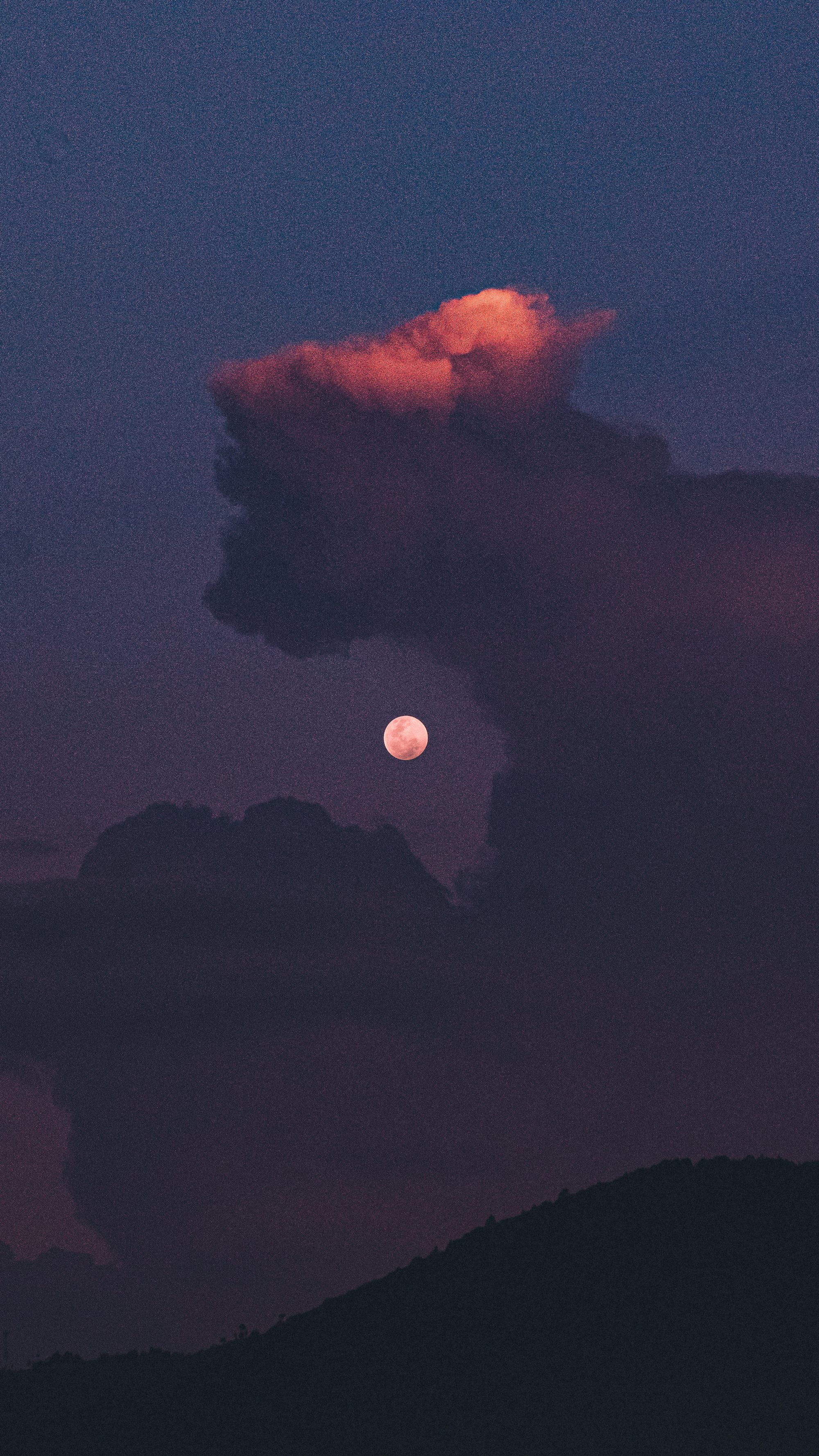 a full moon is seen behind a cloud in the sky