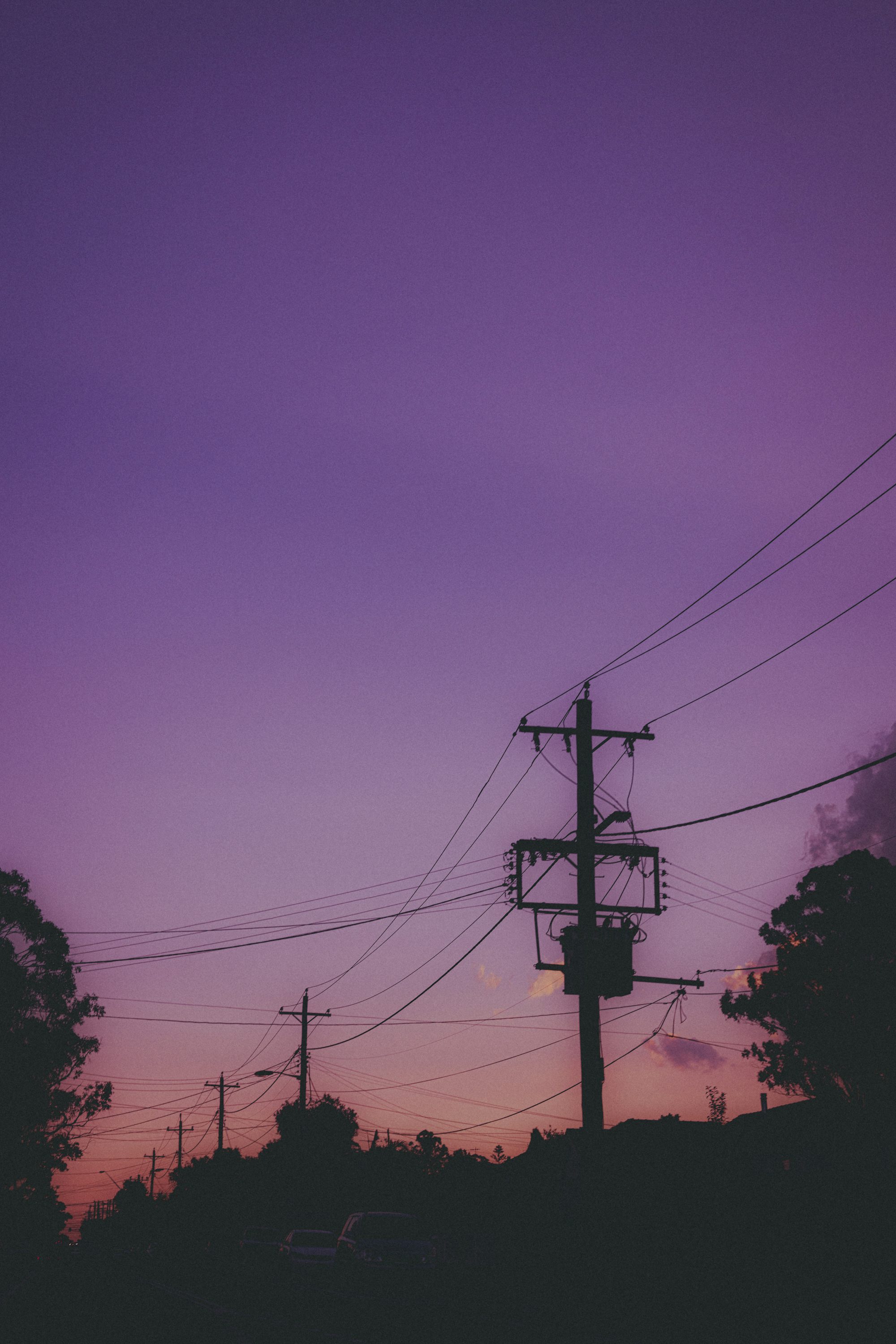 a purple sky with power lines in the foreground