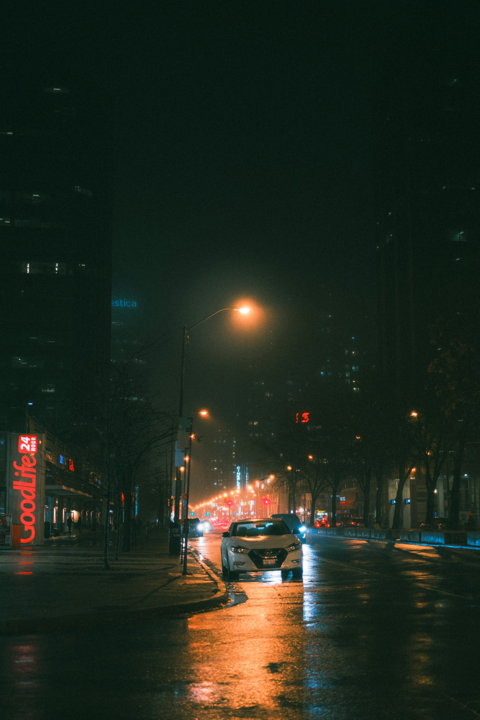 A city street at night with cars driving down it