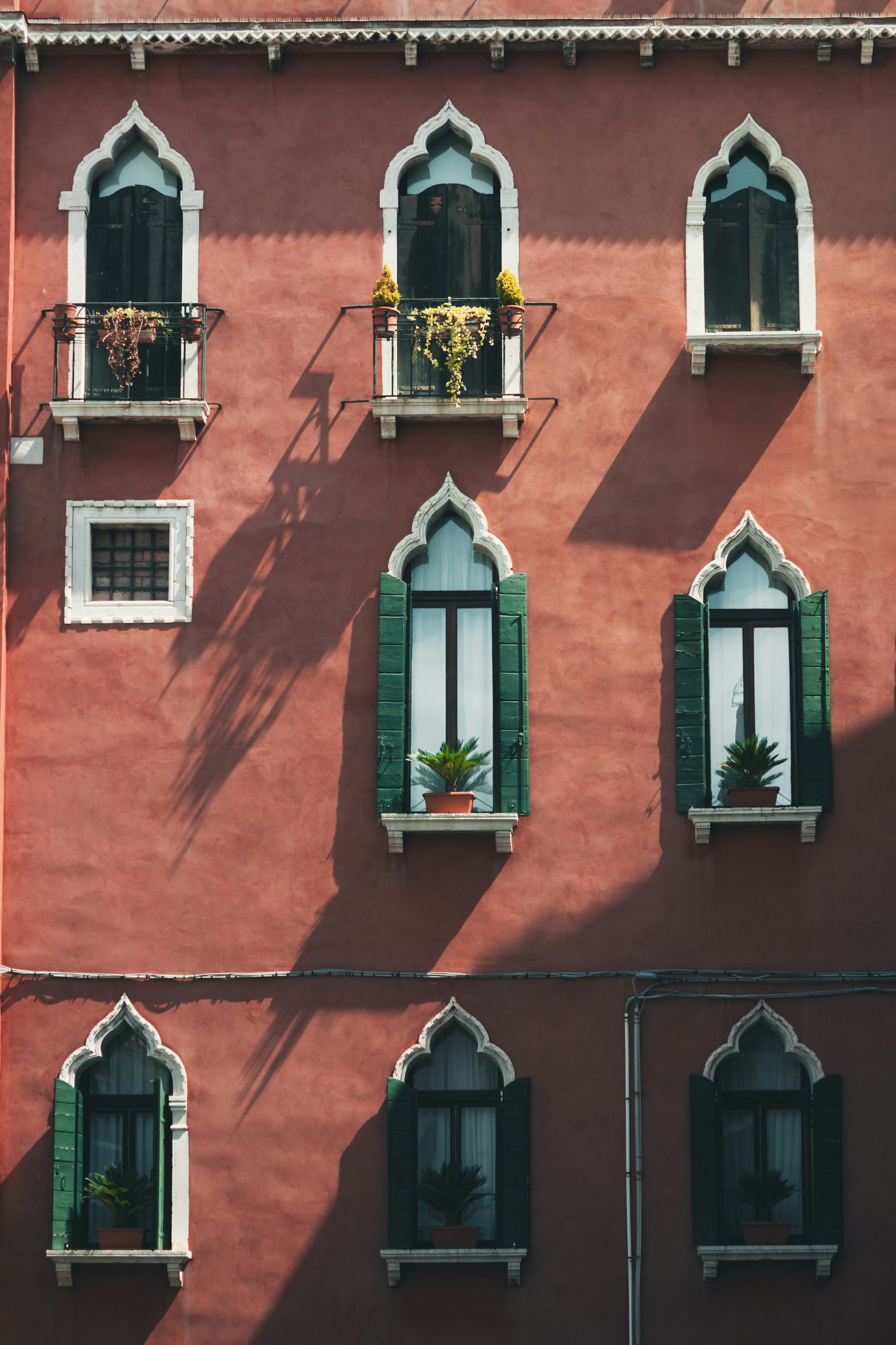 A red building features unique windows and green shutters.