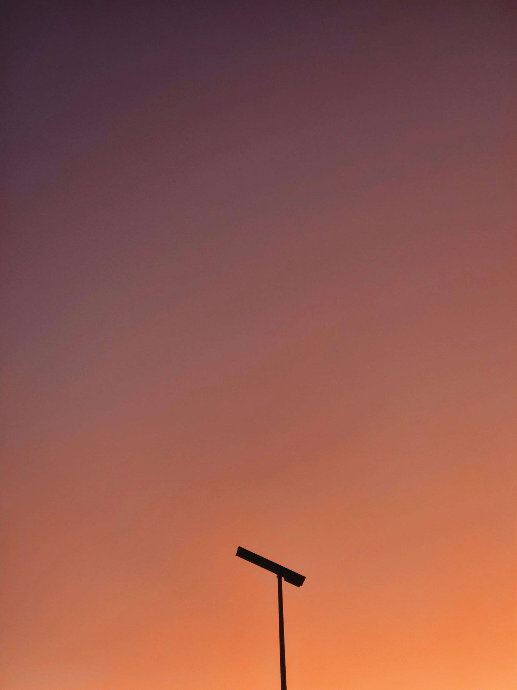 A silhouette of a pole against a sunset sky.